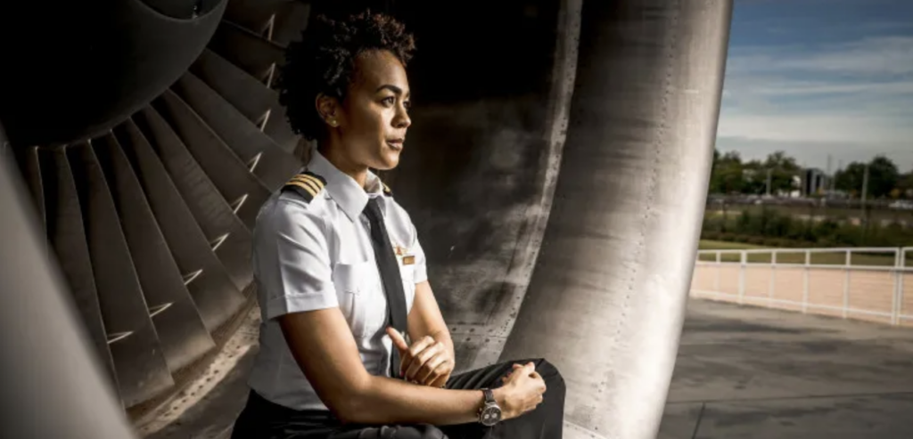 aviation's gender gap, Photo by Terrence Bowen. black airline pilot sitting inside large aircraft engine on tarmac Pexels