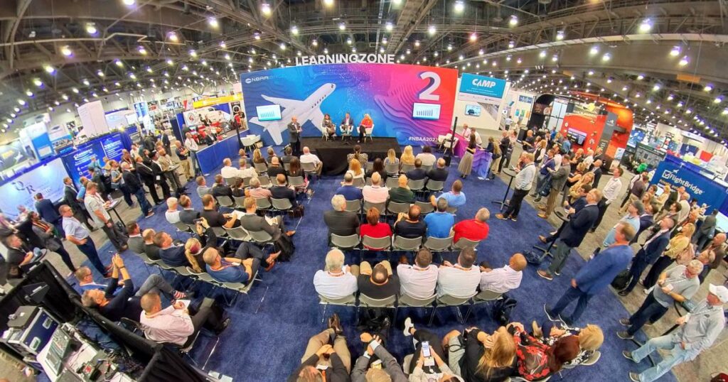 Aerial view of one of the NBAA BACE workforce sessions in 2023 featuring Jennifer E. Pickerel of Aviation Personnel International (API) on stage with standing-room only audience